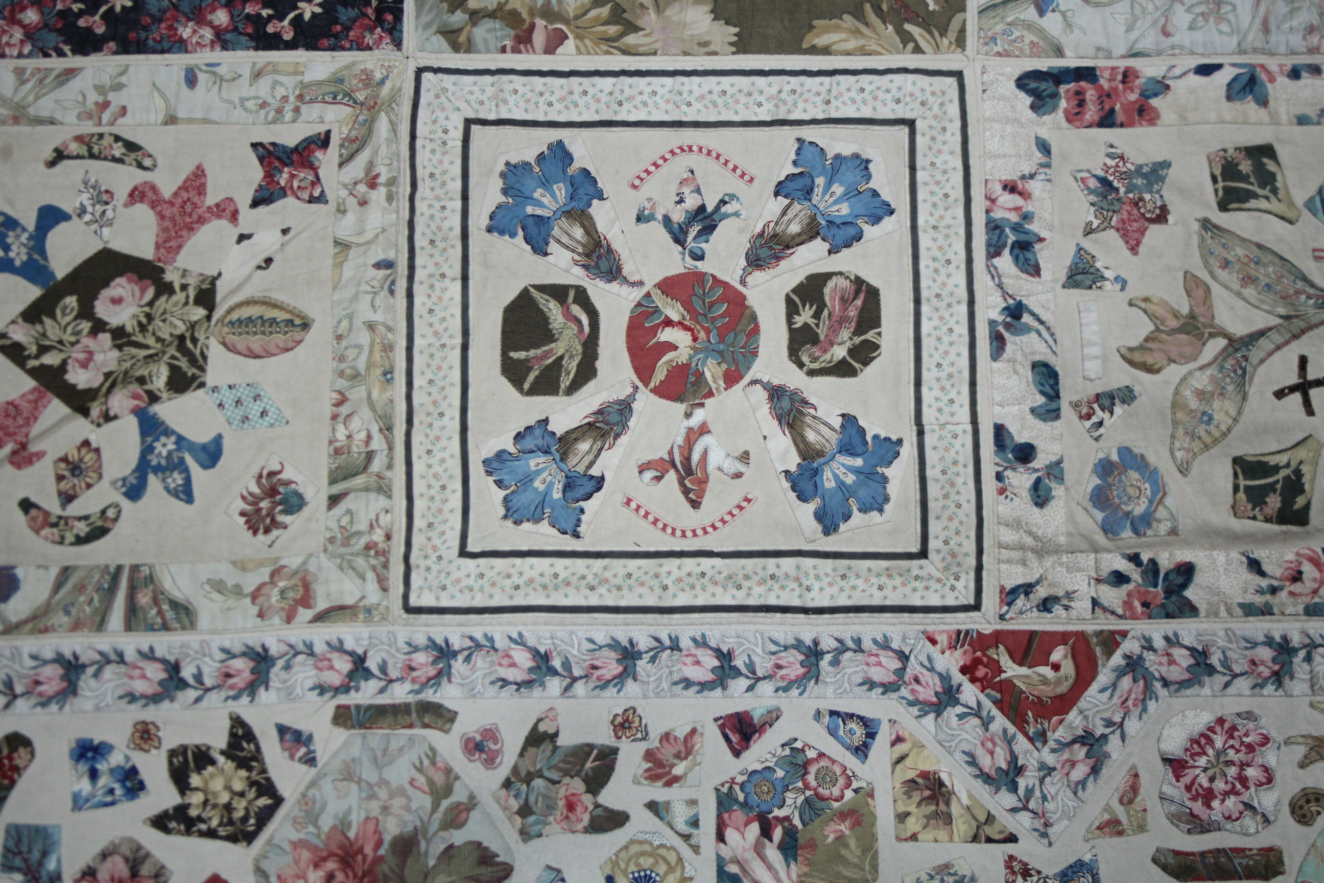 A VICTORIAN PATCHWORK BEDSPREAD or WALL HANGING comprising a wide variety of printed fabrics cut