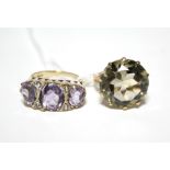 A 9ct. gold ring set three graduated oval amethysts with pairs of small diamonds in between (size