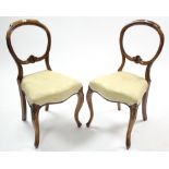 A pair of Victorian carved walnut balloon-back dining chairs with padded seats & on slender cabriole