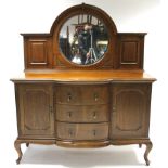 An Edwardian oak break-front mirror-back sideboard, inset bevelled circular plate to the stage back,