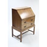 A mid-20th century walnut bureau with fitted interior enclosed by fall-front above two long drawers,