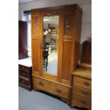 A late Victorian carved walnut wardrobe enclosed by rectangular bevelled mirror door to centre above