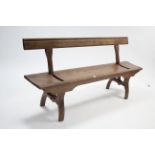 A pine bench with reversible back-rest, & on shaped end supports, 71¾" long.