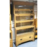 An oak tall standing bookcase enclosed by five glazed doors above a deep long drawer, & with