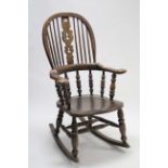 An elm rocking chair with pierced & shaped splat & spindles to the hooped back, with hard seat &