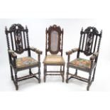 A pair of Carolean-style carved oak elbow chairs with pierced backs, padded seats &on turned legs