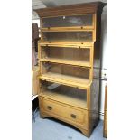 An oak tall standing bookcase enclosed by five glazed doors above a deep long drawer, & with