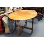 A 1930’s oak oval drop-leaf dining table on barley-twist legs & turned feet with plain stretchers,