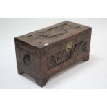 A mid-20th century oriental carved camphorwood small chest with figure scene panels to the hinged