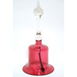 A Victorian cranberry glass large hand bell with tall clear glass handle & later woven leather