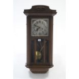 A mid-20th century wall clock with silvered dial, striking movement, & in carved oak case enclosed