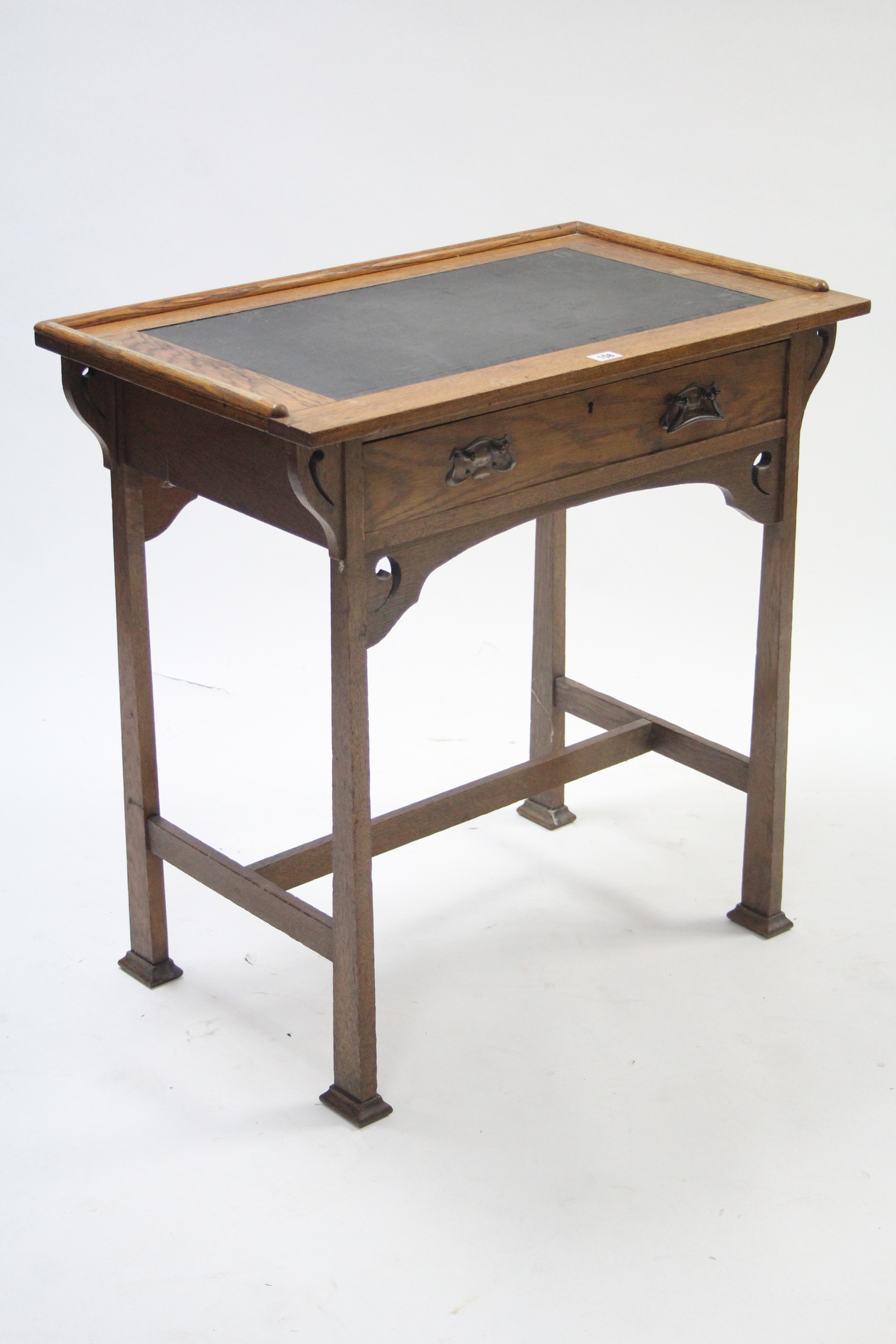 An Edwardian oak small writing table inset tooled leather to the rectangular top, fitted frieze