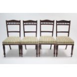 A set of four late Victorian carved walnut spindle-back dining chairs with padded seats & on ring-