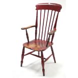 A red stained wooden spindle-back elbow chair with hard seat, & on ring-turned tapered legs with