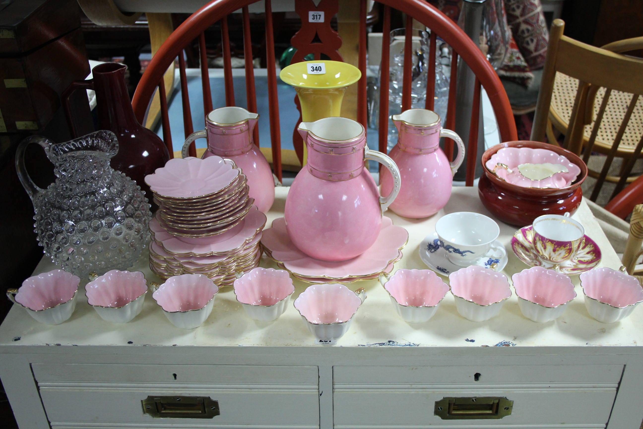 A pink glazed twenty-nine piece part tea service; a similar set of three graduated jugs; a Doulton