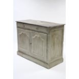 A continental-style grey painted wooden sideboard fitted frieze drawer above cupboard enclosed by