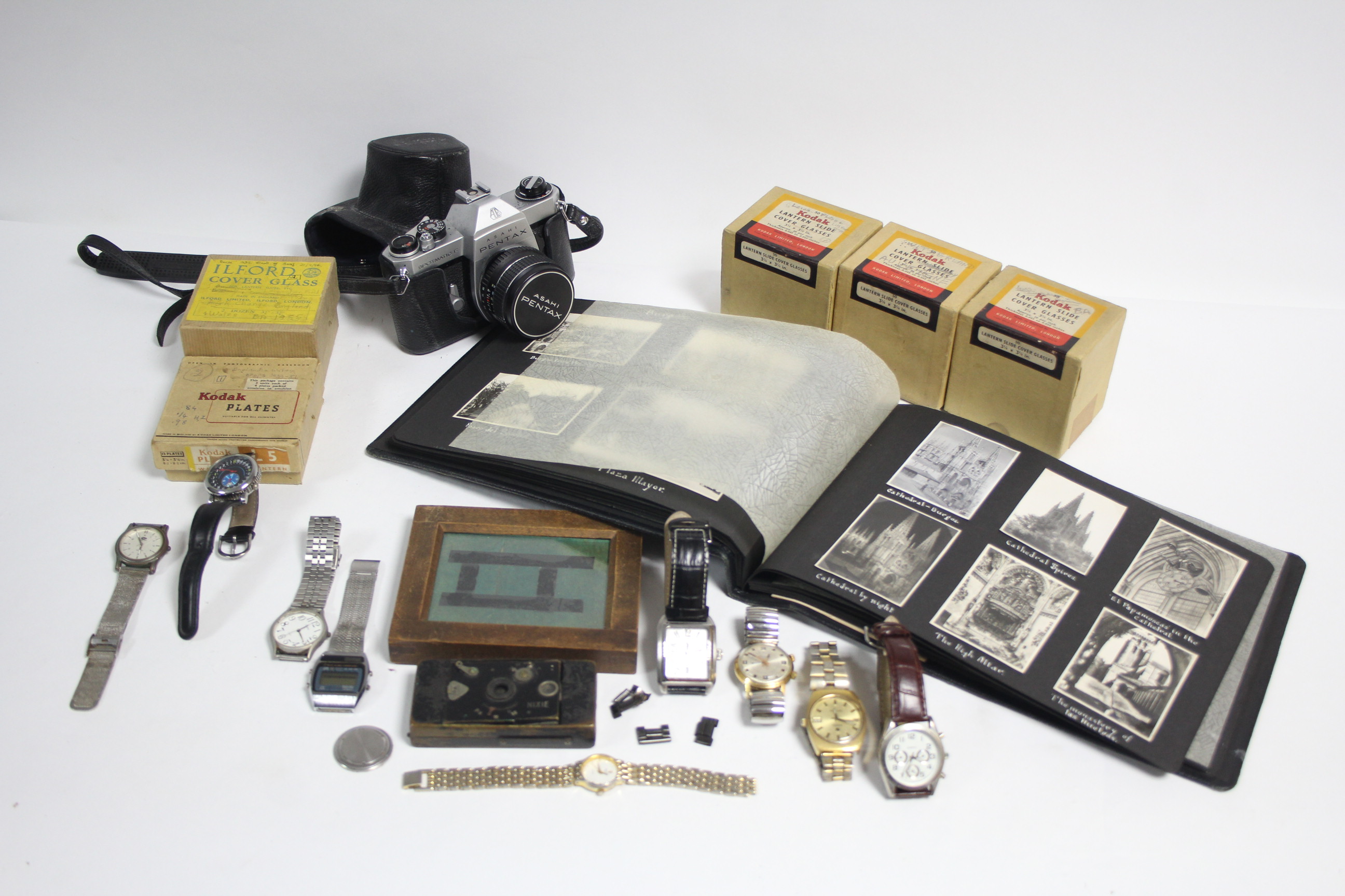 A Nixie small folding camera; an Asahi Pentax “Spotmatic F” camera; five boxes of lantern slides;