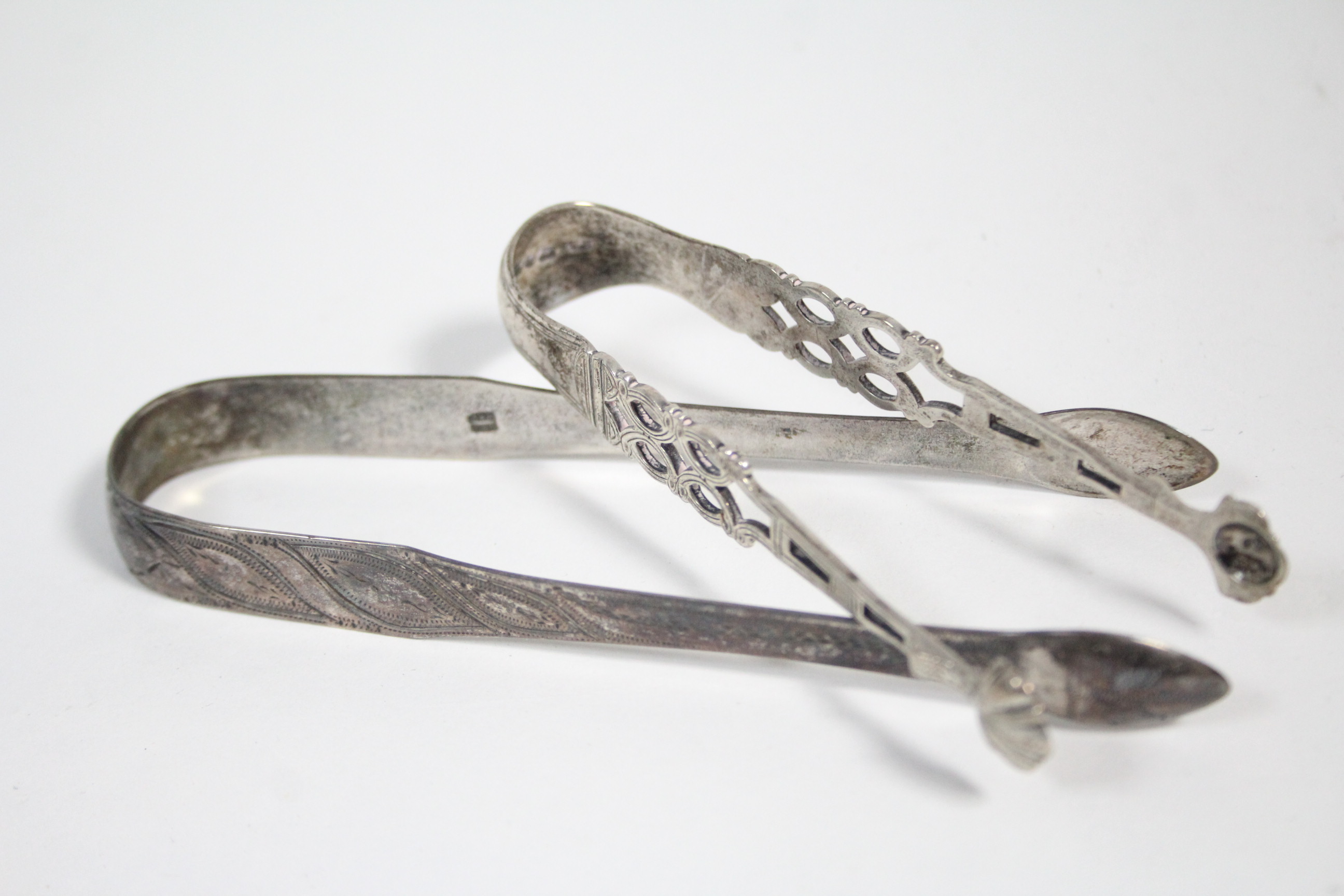 A pair of Victorian sugar tongs in the mid-18th century style, with pierced stems & shell bowls,