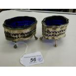 A matched pair of Georgian style silver serpentine outlined salt cellars, having blue glass liners,