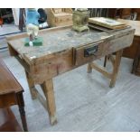 A mid 20thC rustically constructed pine workbench, the planked top with an attached vice,