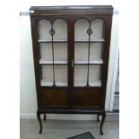 An Edwardian style mahogany finished display cabinet with a pair of glazed doors,