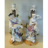 A pair of early 20thC German porcelain candlesticks, one featuring a youth, the other a maiden,