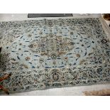 A Persian design carpet with a central medallion of palmets and entwined foliage on a pale blue