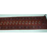 A Bokhara runner with thirteen guls on a red ground 106'' x 27'' S
