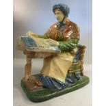 A late 19thC Continental pottery figure, a seated lacemaker, wearing a bonnet,