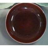 A late 19th/20thC Chinese wine red glazed porcelain footed dish with rounded sides bears a six