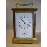 An early/mid 20thC lacquered brass cased carriage clock with bevelled glass panels and a folding