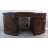 A mid 20thC walnut finished oval desk, having a crossbanded top, three drawers and seven facsimiles,