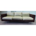 A 1960s three person settee with a low, level back and straight arms, upholstered in cushioned,