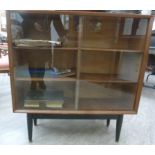 A 1970s teak finished bookcase with a pair of sliding, glazed doors,