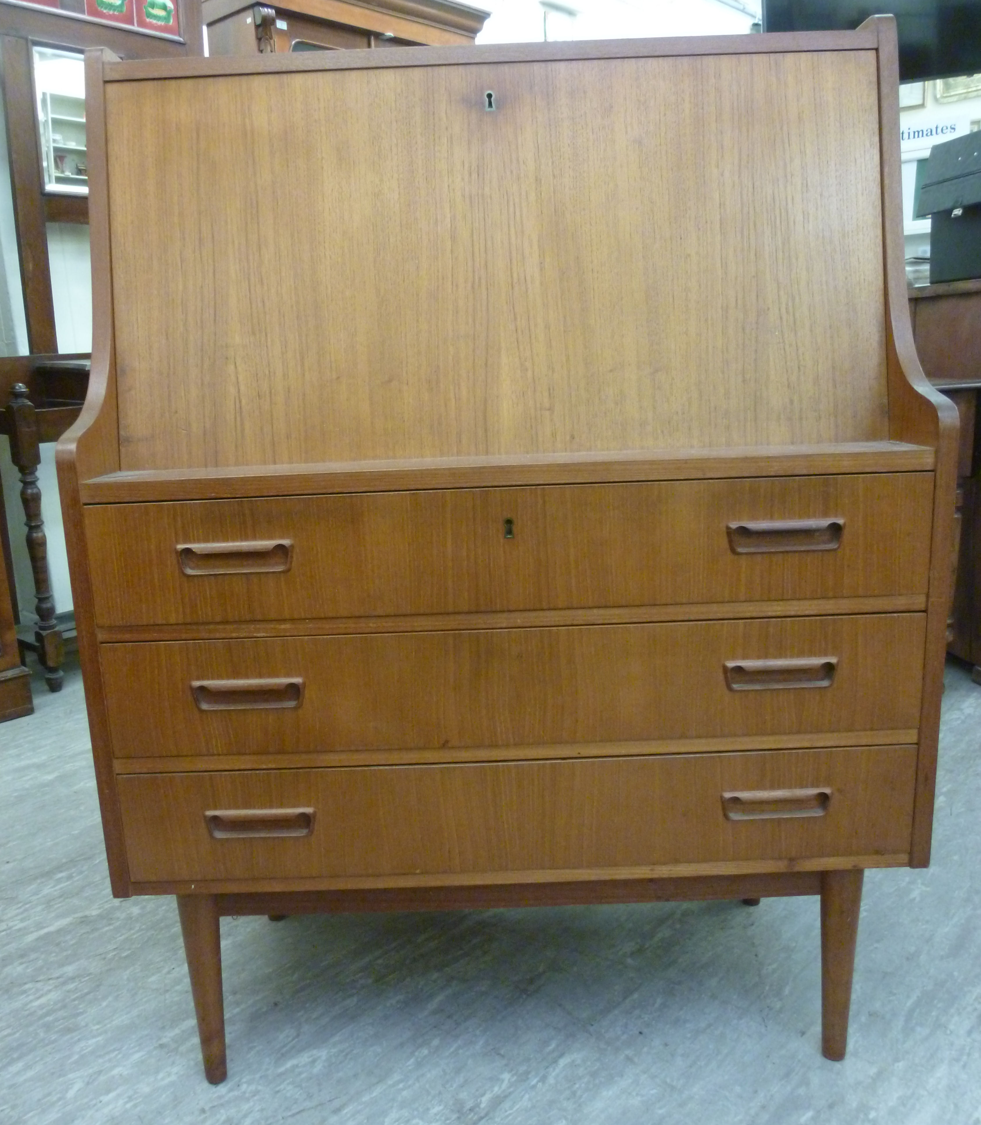 A 1970s teak finished bureau, the fall flap enclosing a fitted interior, over three long drawers,