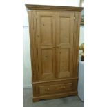 A modern waxed pine wardrobe with a moulded cornice and a pair of panelled doors,