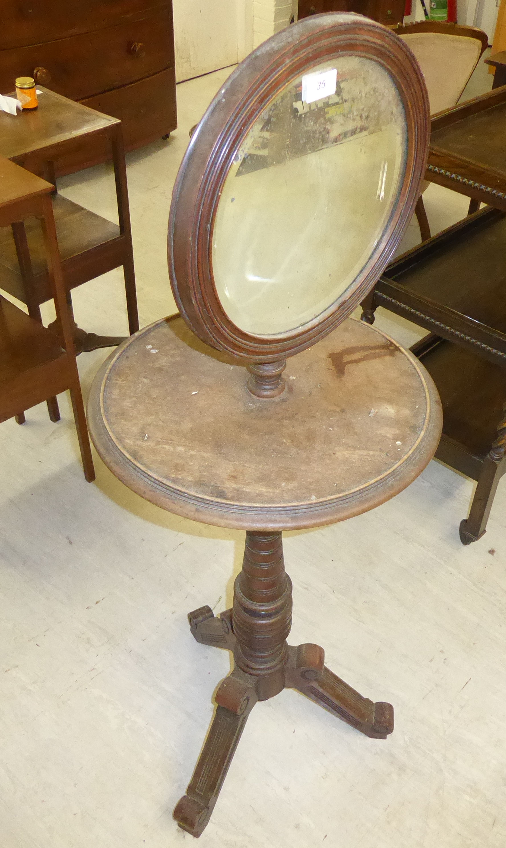 An Edwardian mahogany shaving stand, the rotating circular mirror on a ring turned,