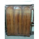 A modern mahogany finished wardrobe with a moulded cornice, over three doors,