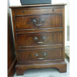 A modern mahogany finished bedside cabinet with a brushing slide, over three drawers,