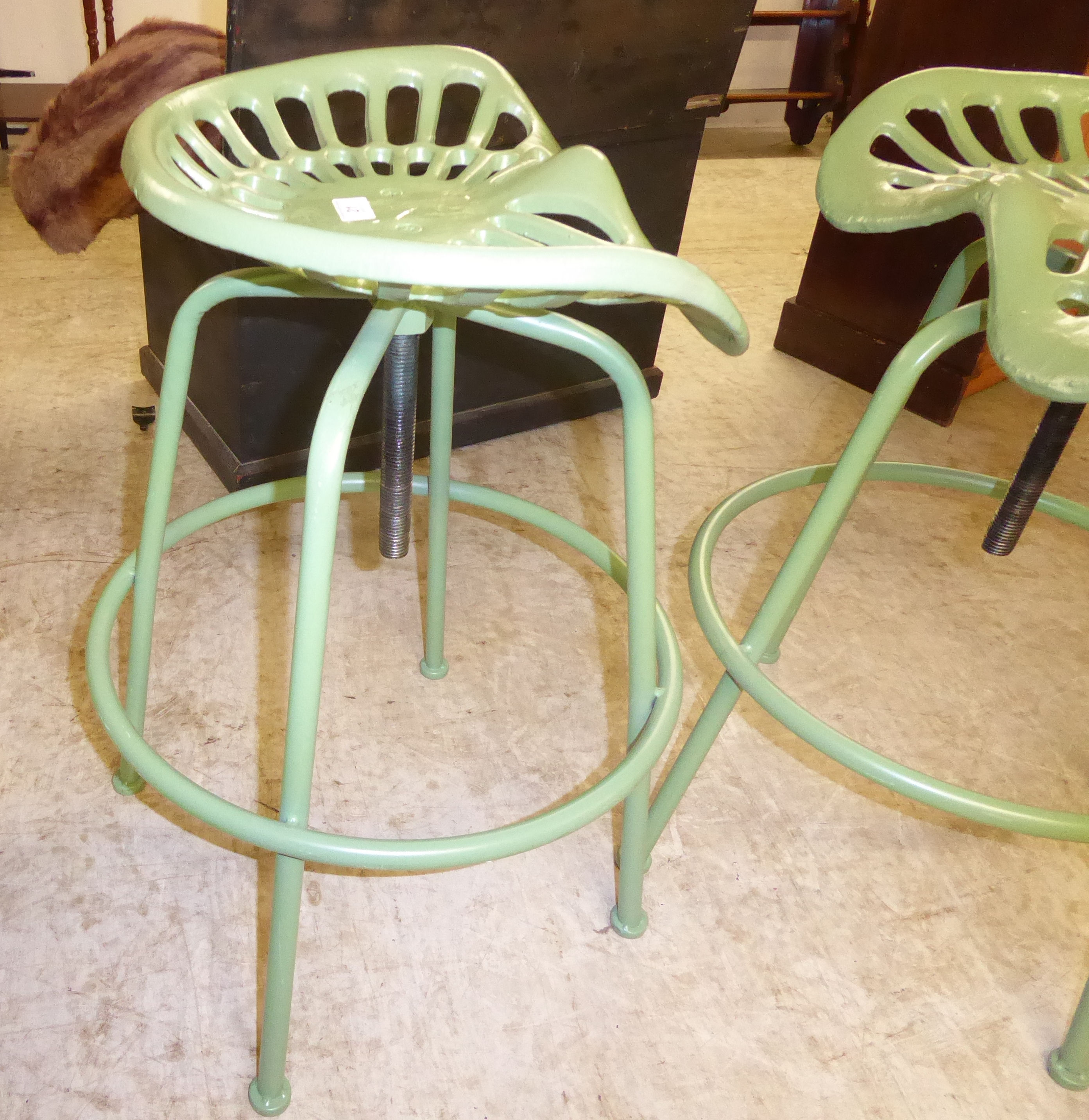 An (as new) green painted cast iron and steel stool with a height adjustable tractor style seat,