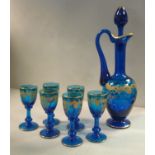 A semi-opaque midnight blue glass liqueur set, decorated in gilt with flora and scrolled foliage,