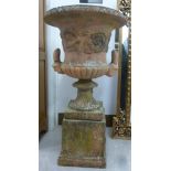 A late 19th/early 20thC terracotta twin handled campana design terrace urn with mask and foliate