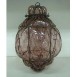 A late Victorian ruby coloured glass hanging light with a wrought metal wire frame 18''h