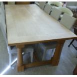 A modern, washed honey coloured oak refectory style table, the planked top raised on ring turned,