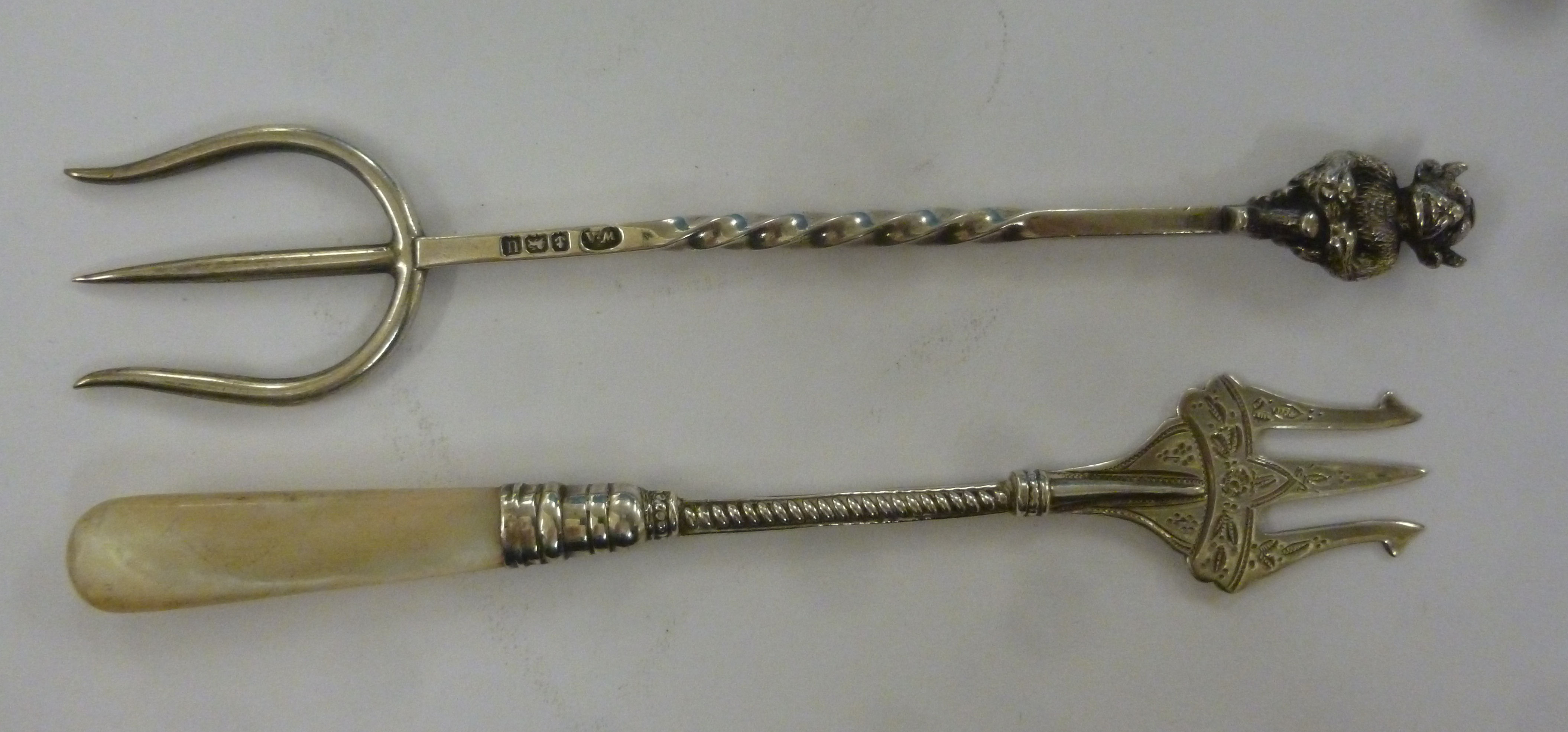 Two silver trident forks, one with a square,