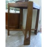 An early 20thC Arts & Crafts light oak side table, the top having canted corners, a wide,