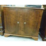 A mid 20thC Masters of Eton yew wood finished hi-fi cabinet with a pair of rising flaps,