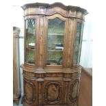 A modern walnut finished bow front display cabinet with a level and central arched cornice,