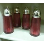 Four identical, faceted, tapered cylindrical Cranberry glass casters with domed,