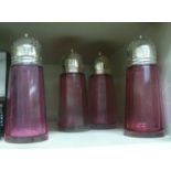 Four identical, faceted, tapered cylindrical Cranberry glass casters with domed,